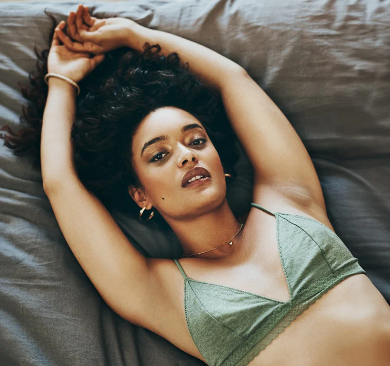 woman in green bra on her bed | Henderson Breast Reconstruction New York