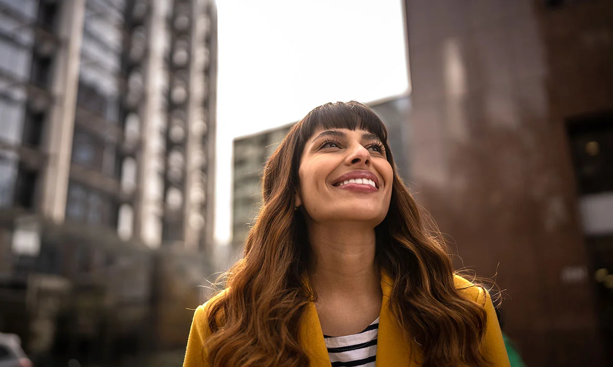 Woman downtown looking up and smiling - Hybrid Breast Reconstruction