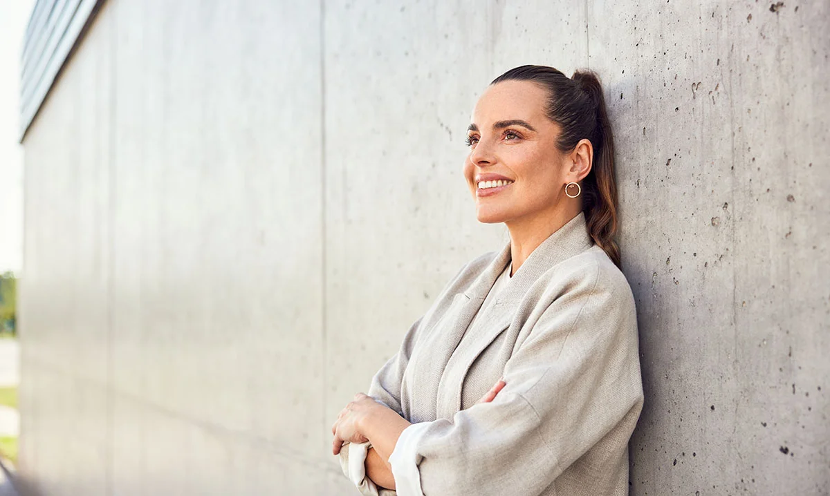Woman leaning against a concrete wall - Implant Based Breast Reconstruction